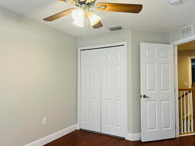 an empty room with wooden floor closet and windows