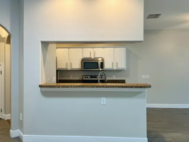 a view of kitchen island with stainless steel appliances granite countertop refrigerator sink and stove