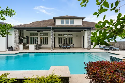 a view of a house with pool and chairs