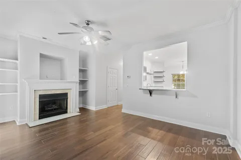 a view of an empty room with wooden floor and a fireplace