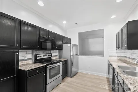 a kitchen with granite countertop a refrigerator and a sink