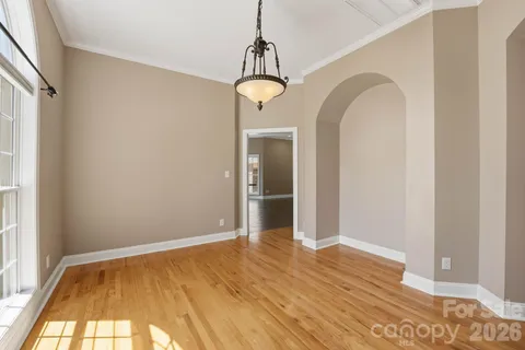 a view of an empty room with wooden floor and fan