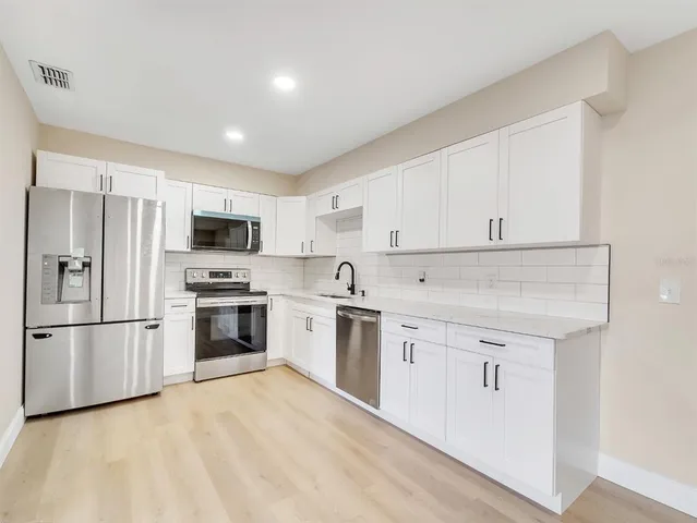 a kitchen with white cabinets and stainless steel appliances