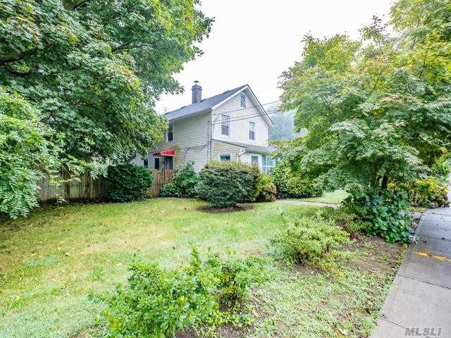 a view of a house with a small yard and large trees