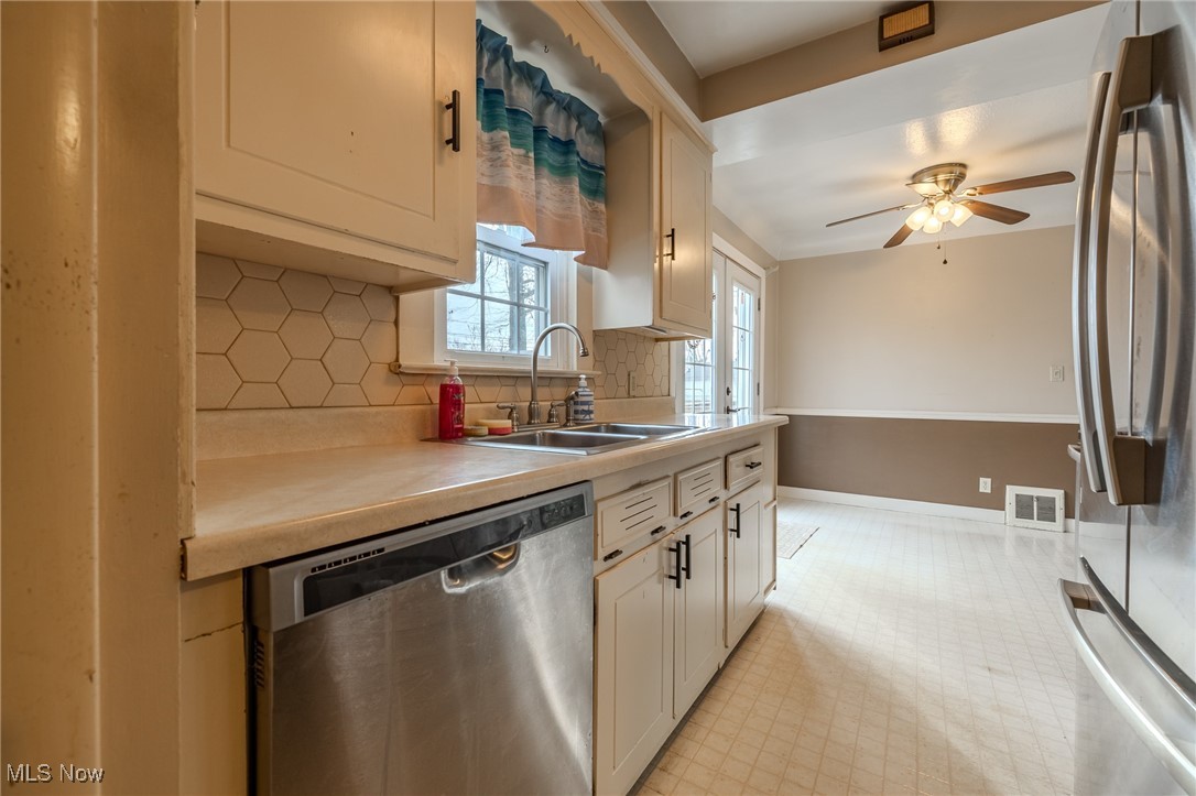 765 Pendley Road Willowick, OH 44095 - Photo 30 of 50 Kitchen featuring backsplash, stainless steel appliances, ceiling fan, sink, and white cabinetry