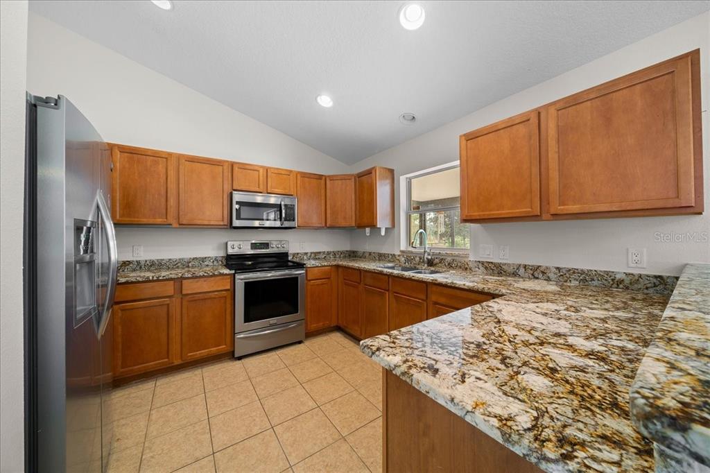 234 Locust Lane Ocala, FL 34472 - Photo 46 of 71 a kitchen with stainless steel appliances granite countertop a stove top oven a sink dishwasher and a microwave oven on the blue kitchen countertops