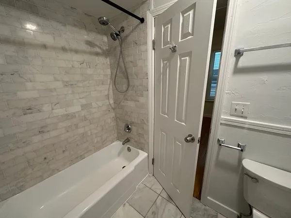 a bathroom with a tub a toilet and a shower
