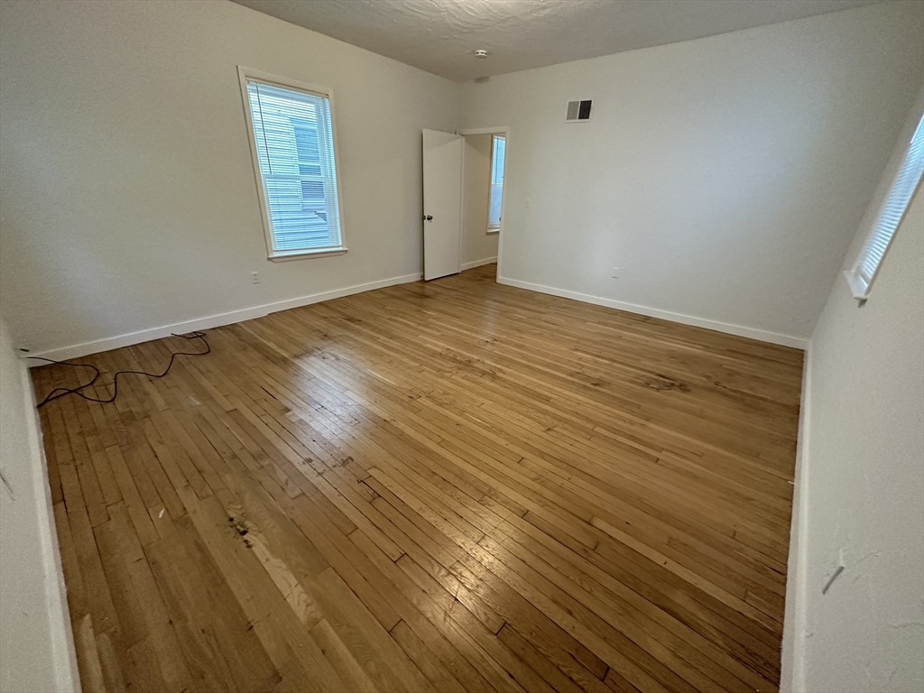 303 Hancock Street, Unit 2 Boston, MA 02125 - Photo 7 of 8 a view of an empty room with window and wooden floor