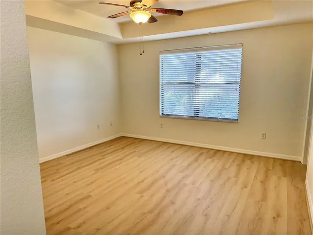 an empty room with a chandelier fan and windows