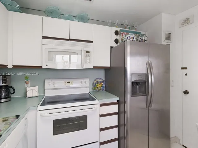 a kitchen with stainless steel appliances granite countertop a refrigerator a stove and a sink