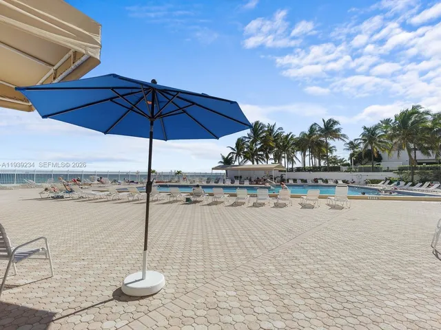 a view of a swimming pool with a table and chairs under an umbrella