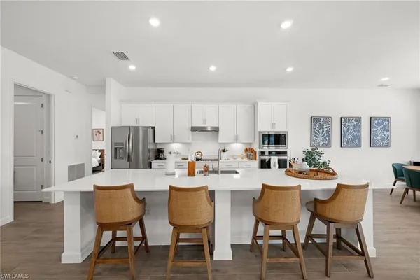 a dining room with stainless steel appliances a dining table and chairs