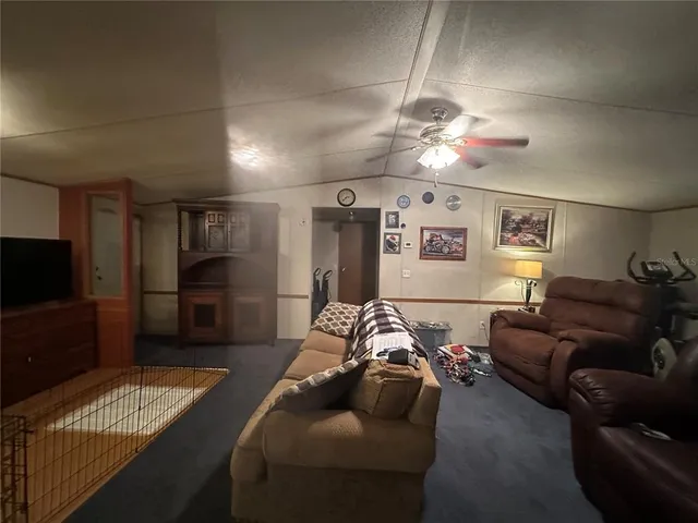 a living room with furniture a flat screen tv and kitchen view