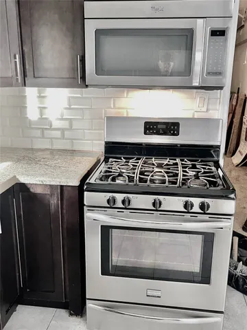 a kitchen with granite countertop cabinets stove and microwave