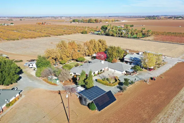 an aerial view of a house with a yard and large trees