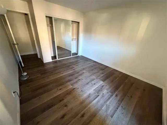 an empty room with wooden floor and entrance