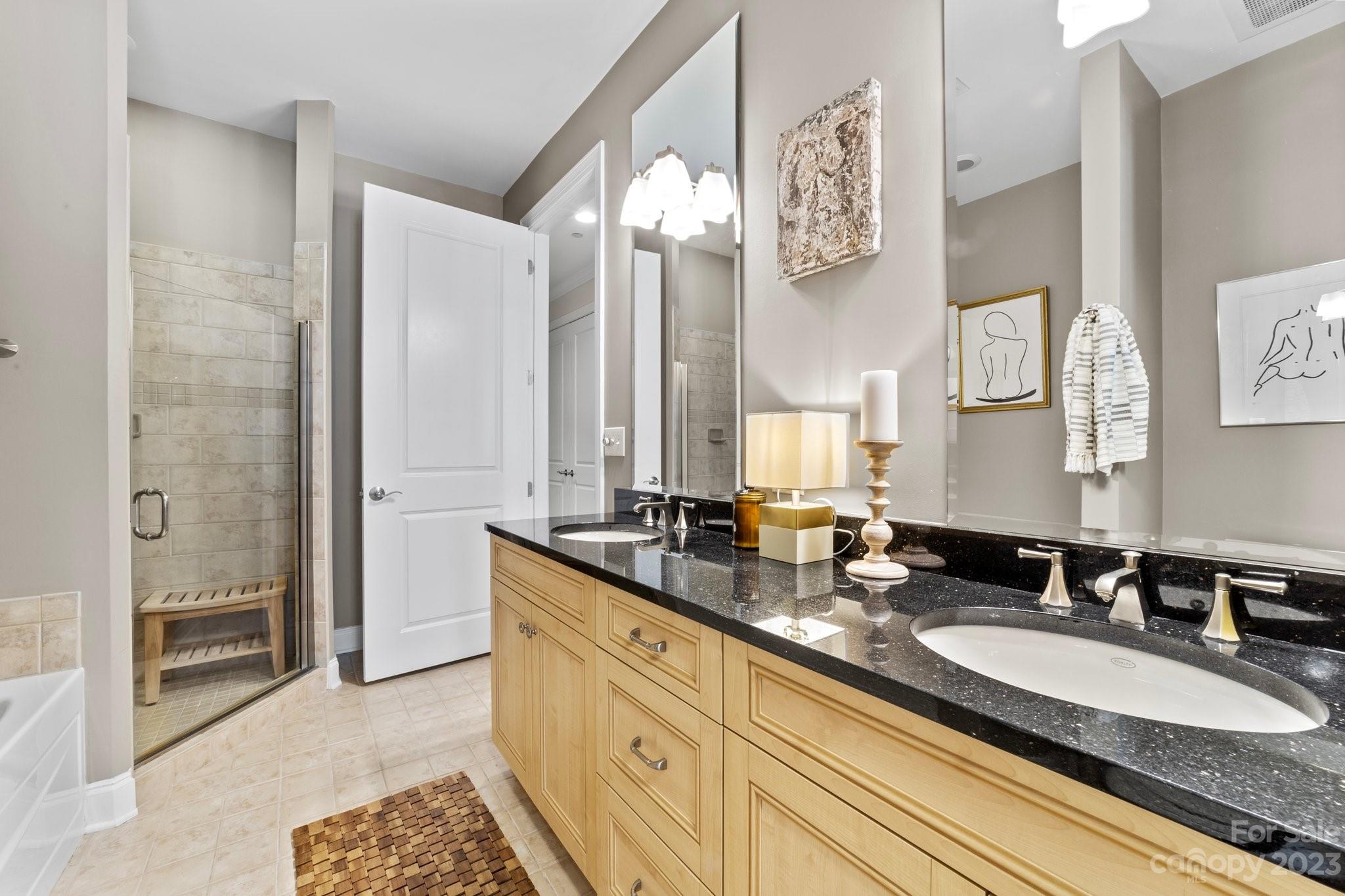 230 South Tryon Street, Unit 906 Charlotte, NC 28202 - Photo 16 of 27 a bathroom with double vanity sinks a mirror and a shower
