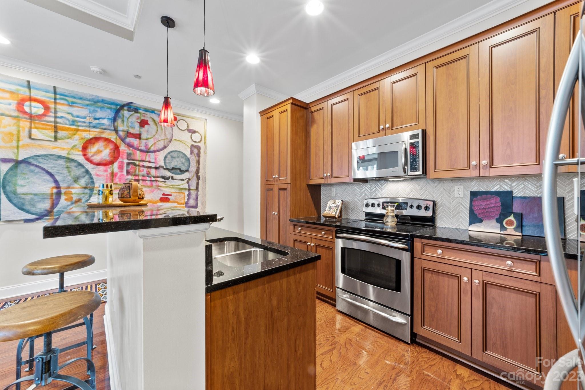 230 South Tryon Street, Unit 906 Charlotte, NC 28202 - Photo 5 of 27 a kitchen with stainless steel appliances granite countertop a stove a sink and a microwave