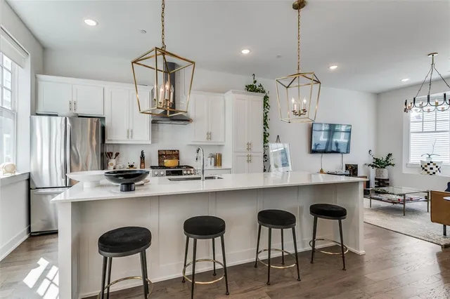 a kitchen with stainless steel appliances a dining table chairs refrigerator and microwave