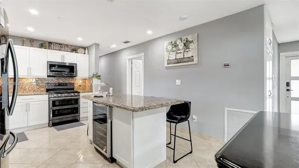 a kitchen with stainless steel appliances kitchen island granite countertop a kitchen island and chairs in it