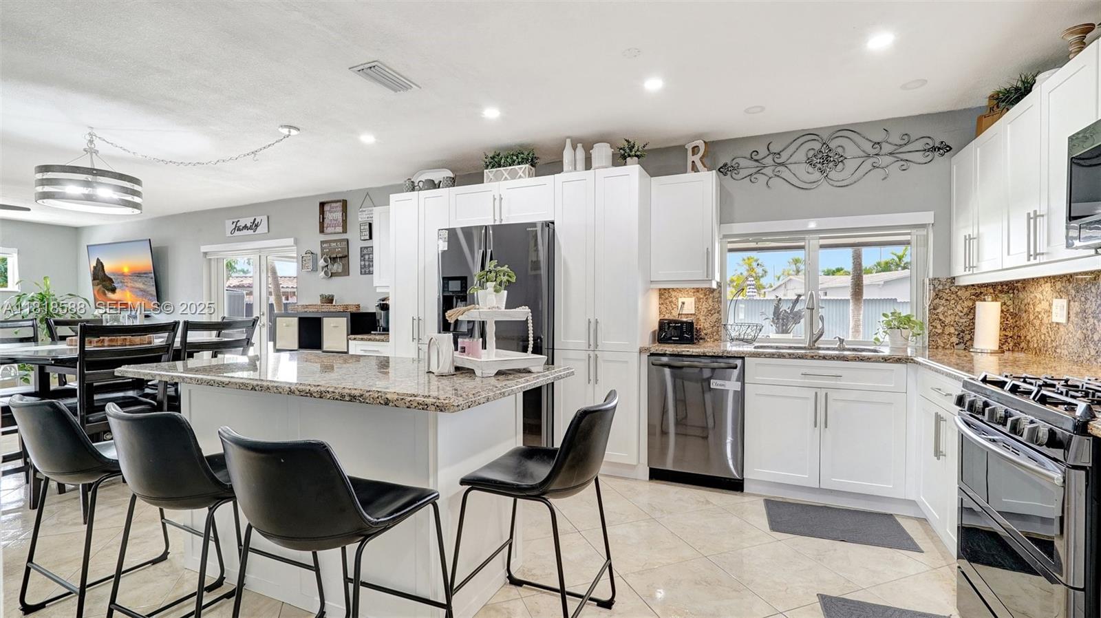 8540 Northwest 182nd Street Hialeah, FL 33015 - Photo 16 of 63 a kitchen with stainless steel appliances kitchen island granite countertop a kitchen island and chairs in it