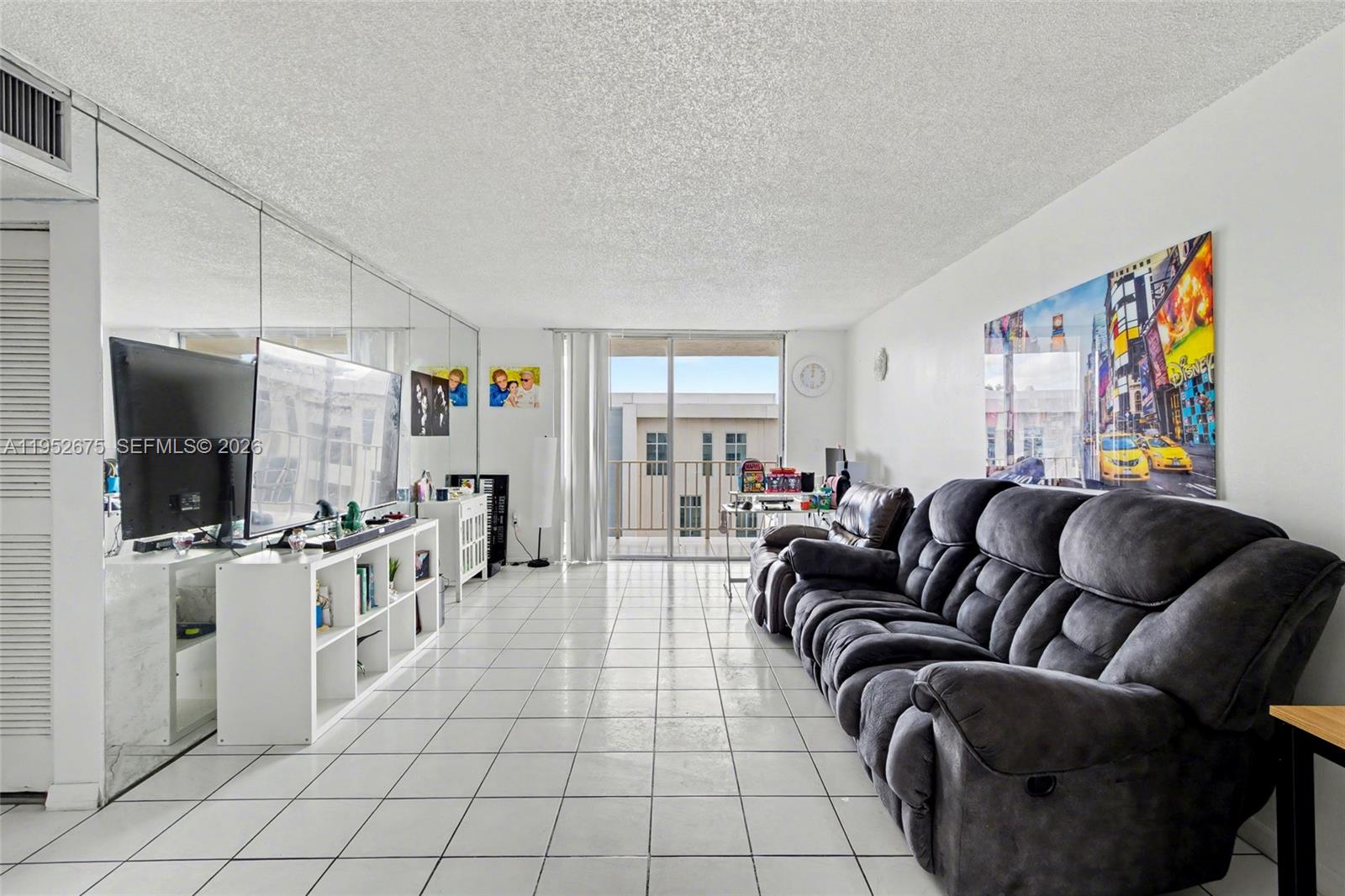 4675 West 18th Court, Unit 701 Hialeah, FL 33012 - Photo 2 of 14 a living room with furniture and a flat screen tv