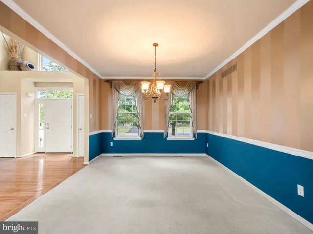 a view of an empty room with window and chandelier