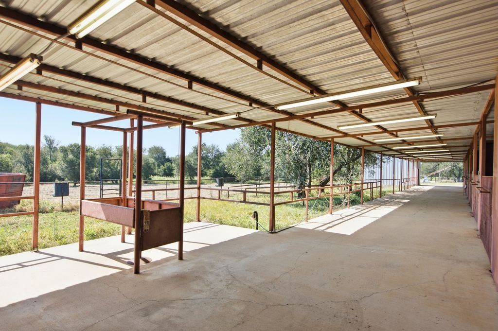1454 Red Town Road Elgin, TX 78621 - Photo 27 of 40 A spacious, covered barn with ample room for horses, featuring sturdy metal construction and open views of the surrounding pastures.