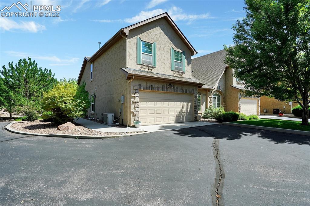 6578 Bethesda Point, Unit B Colorado Springs, CO 80918 - Photo 2 of 45 a front view of a house with a yard and garage