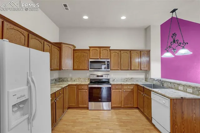 a kitchen with stainless steel appliances granite countertop a refrigerator a stove a sink and a microwave