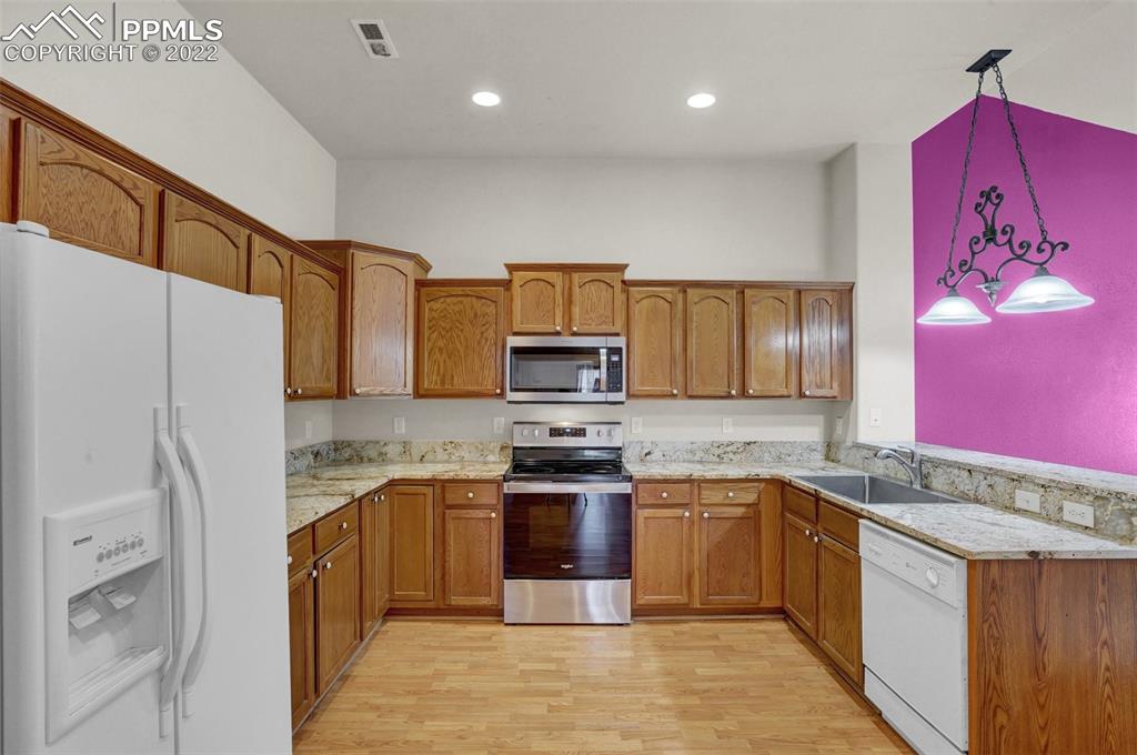 6578 Bethesda Point, Unit B Colorado Springs, CO 80918 - Photo 21 of 45 a kitchen with stainless steel appliances granite countertop a refrigerator a stove a sink and a microwave