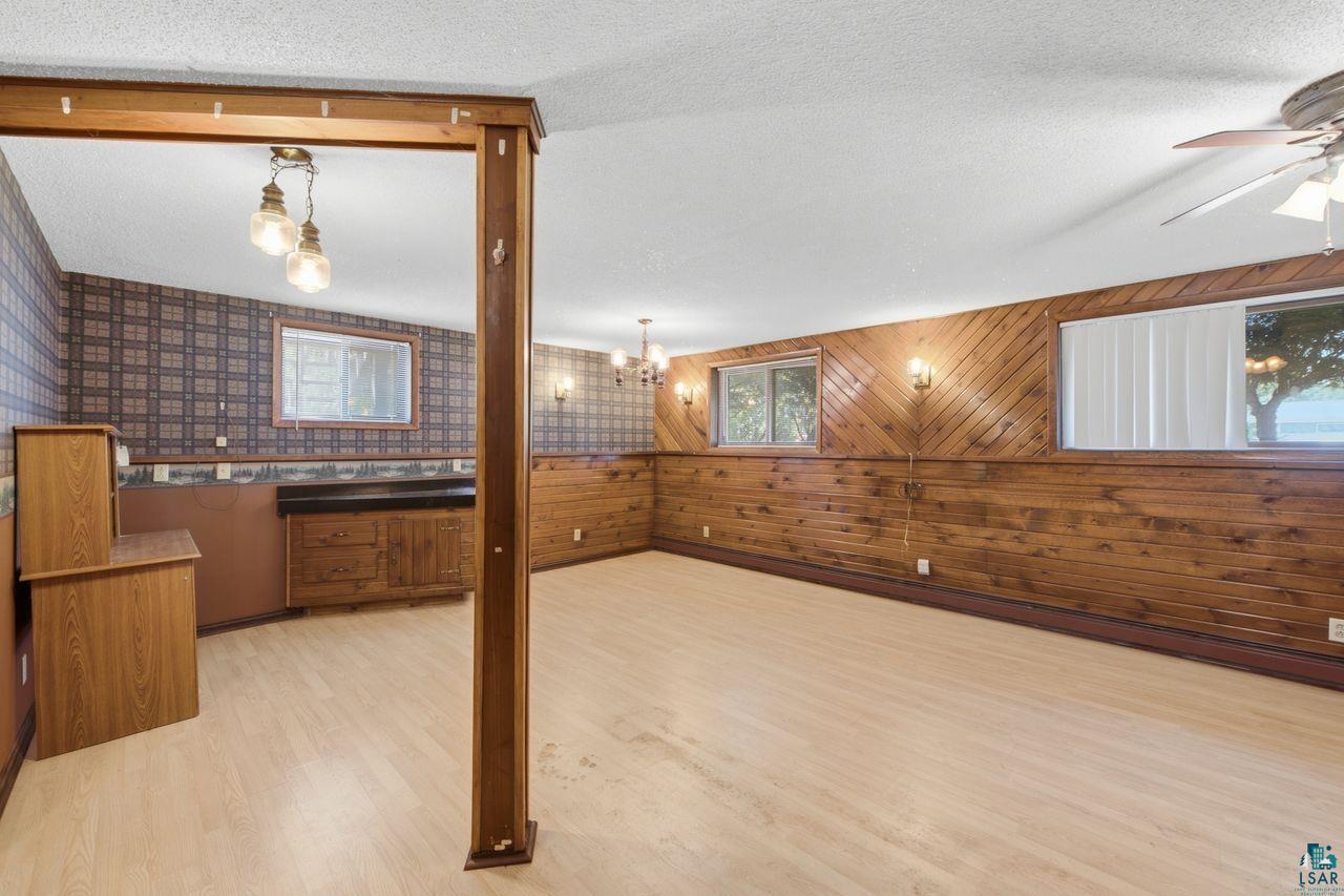 61018 Dahlstrom Road Ashland, WI 54806 - Photo 17 of 28 Spacious room featuring light wood-finish flooring, wood paneling, and an exposed wooden beam