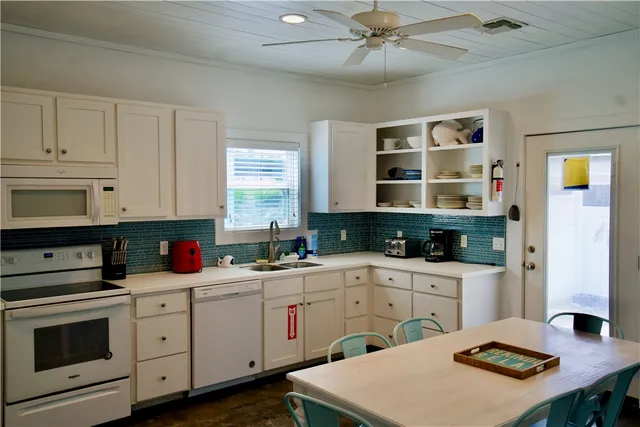 a kitchen with a sink dishwasher and white cabinets with wooden floor