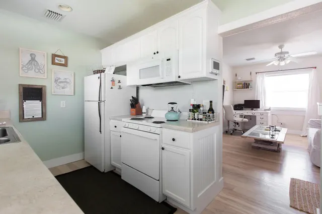 a kitchen with stainless steel appliances white cabinets and wooden floor