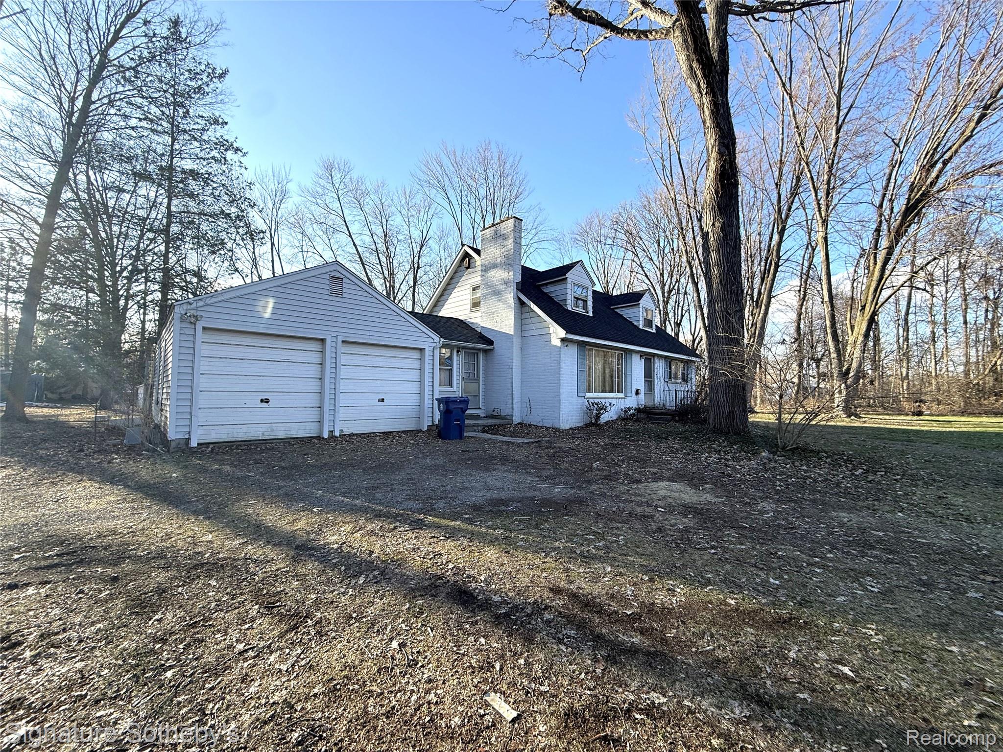 5825 North Lotz Road Canton, MI 48187 - Photo 3 of 10 View of property exterior featuring dirt driveway, a chimney, and an attached garage