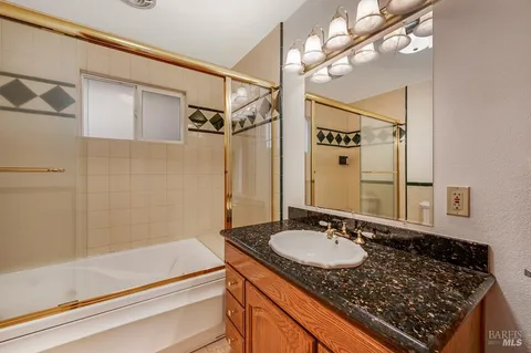 a bathroom with a granite countertop sink a mirror and a shower
