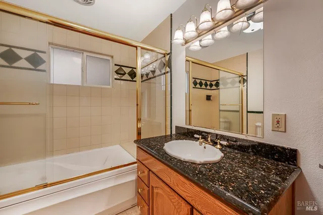 a bathroom with a granite countertop sink a mirror and a shower