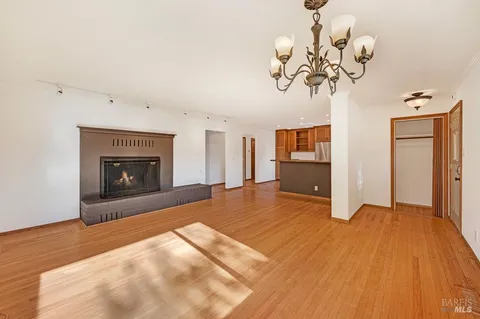 a view of a livingroom with a fireplace a chandelier and wooden floor