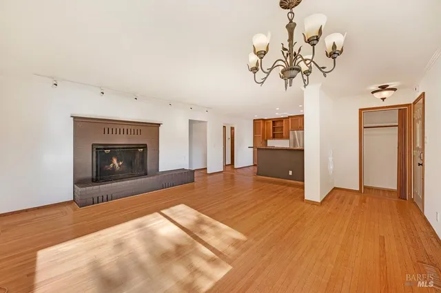 a view of a livingroom with a fireplace a chandelier and wooden floor