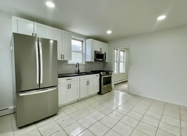 a kitchen with granite countertop a refrigerator and a stove top oven