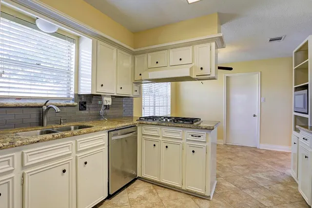 a kitchen with granite countertop a sink stove and cabinets