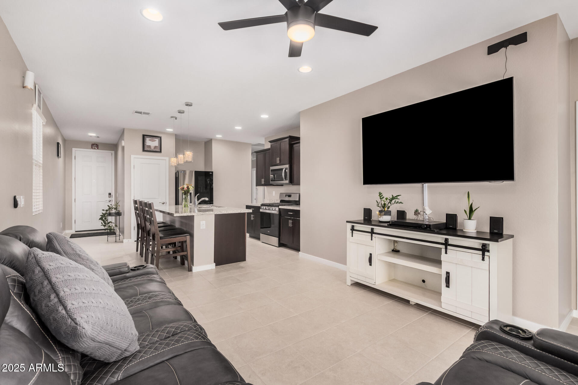 10736 West Chipman Road Tolleson, AZ 85353 - Photo 8 of 27 a kitchen with stainless steel appliances kitchen island granite countertop a stove top oven a sink a dining table and chairs with wooden floor