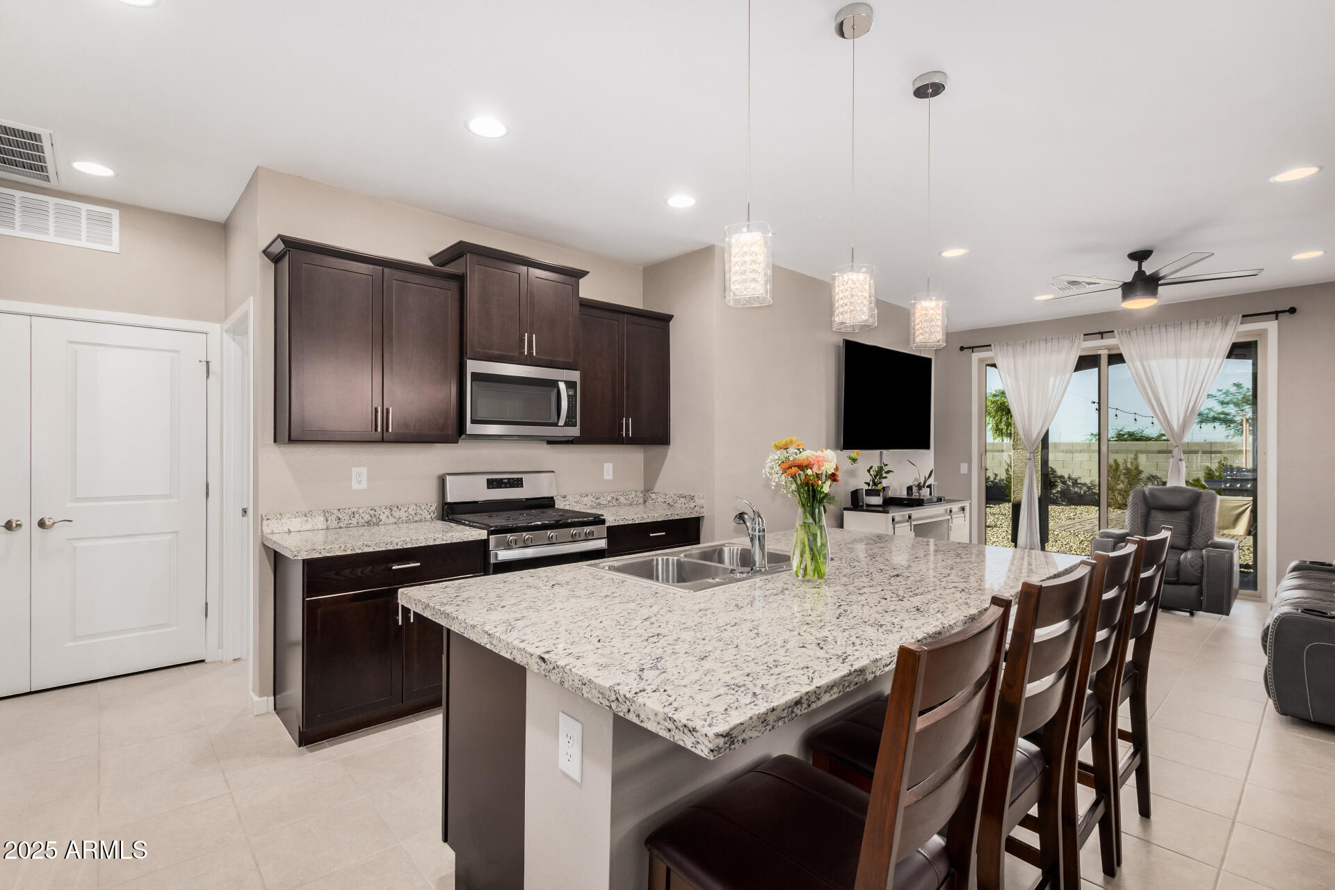 10736 West Chipman Road Tolleson, AZ 85353 - Photo 9 of 27 a kitchen with stainless steel appliances granite countertop a stove top oven a sink dishwasher a dining table and chairs with wooden floor