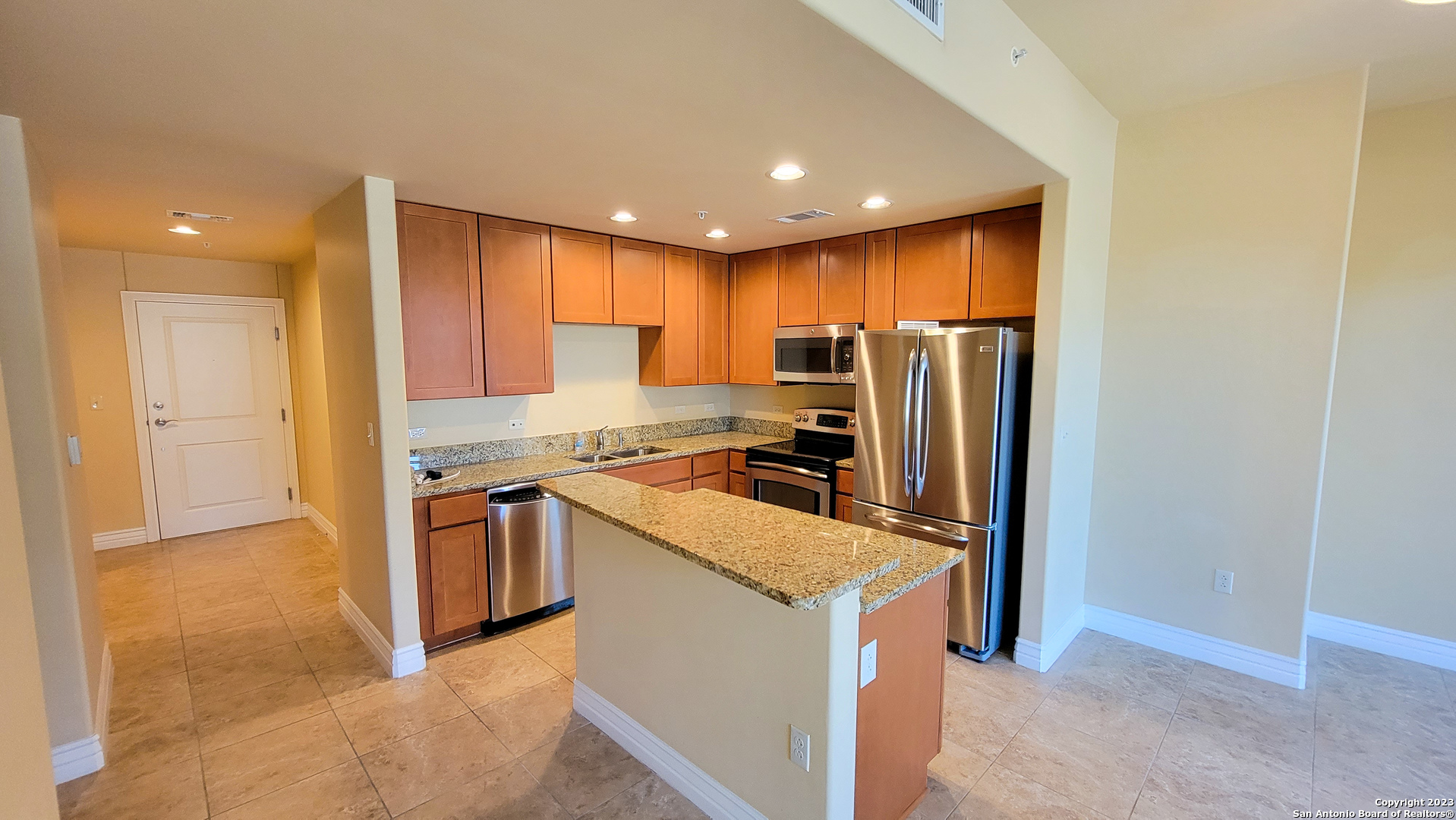a kitchen with stainless steel appliances granite countertop a refrigerator a sink a stove and a microwave