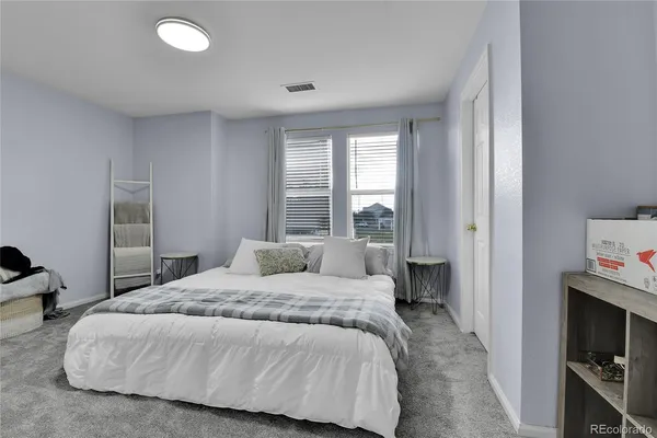 a bedroom with a bed and a flat tv screen next to a window