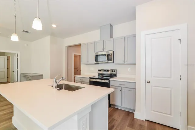 a kitchen with a sink a stove a refrigerator and white cabinets