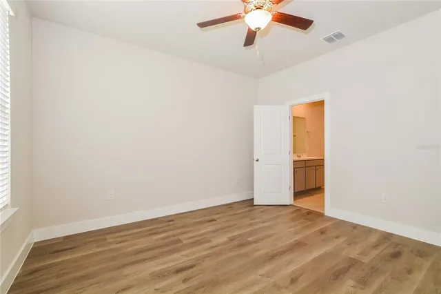 an empty room with a ceiling fan and wooden floor