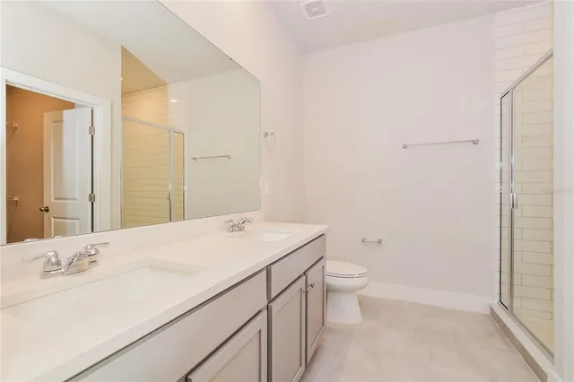 a bathroom with a sink a toilet and a large mirror