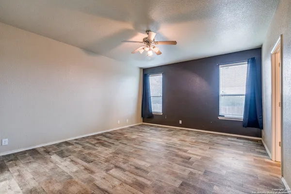 a view of empty room with wooden floor and fan