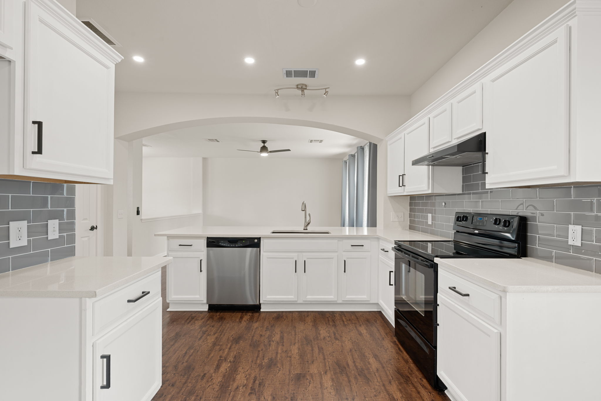 8902 Magna Carta Loop, Unit 122 Austin, TX 78754 - Photo 11 of 39 A well-appointed kitchen features white cabinetry, sleek appliances, and durable flooring, opening into a spacious living area.